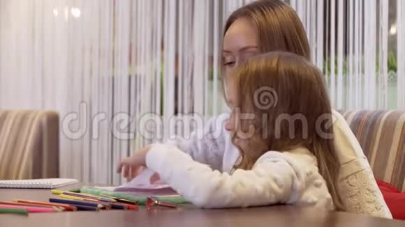 积极的年轻女子和她美丽的小女儿一起画画视频的预览图