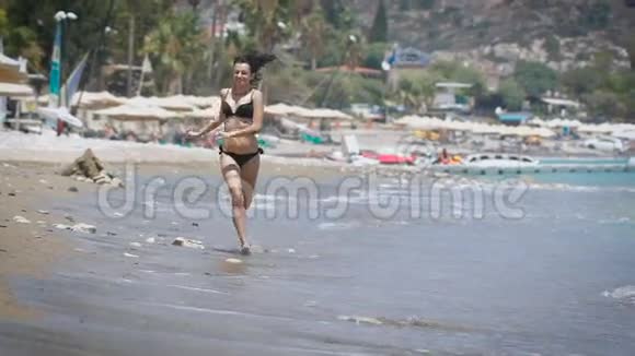 一位美丽的年轻女子在塞浦路斯的海滩上奔跑视频的预览图