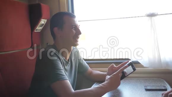 男子旅行者在火车上放松听音乐通过社交媒体微笑缓慢的生活方式视频的预览图