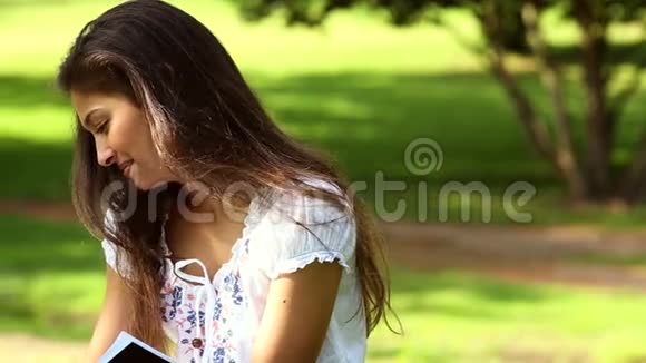 坐在草地上学习的漂亮女孩视频的预览图