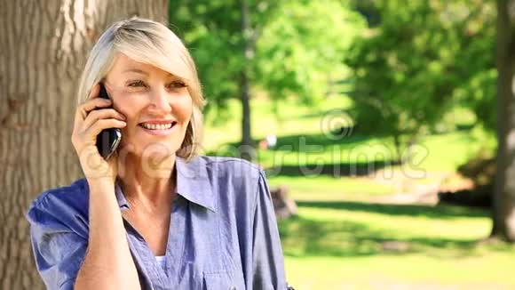 快乐的女人在公园里用电话聊天视频的预览图