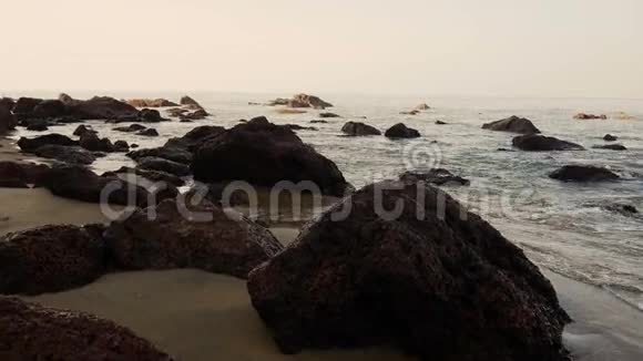 在海滩边的岩石间散步的年轻活泼的女人视频的预览图