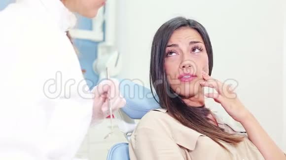 接近与牙医谈话并显示牙齿疼痛的女性病人视频的预览图