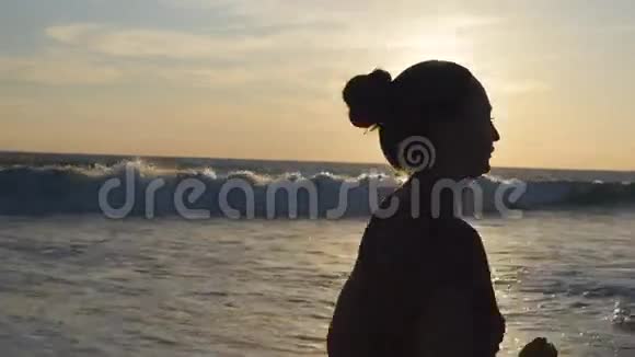 日落时在海边奔跑的年轻女子剪影日出时沿着海岸慢跑的女孩女性视频的预览图