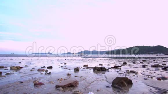 沙滩在退潮时海浪反射日落的光背景中的游艇4K广角镜头视频的预览图