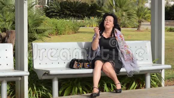 孤独的女人在公园的长凳上抽烟视频的预览图