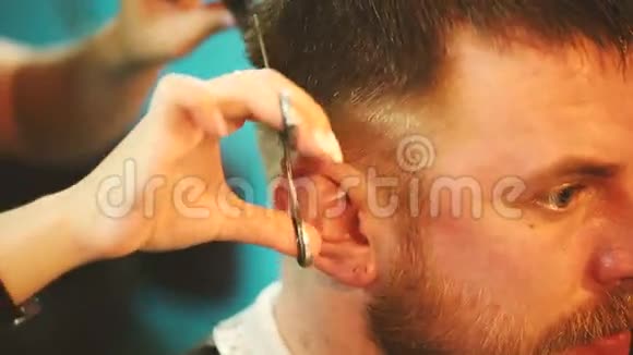 理发师用剪刀剪一个年轻的头发视频的预览图