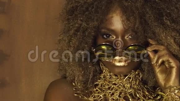 美国黑人女模特戴着巨大的太阳镜浓妆艳抹金色的发式和红色的大嘴唇视频的预览图