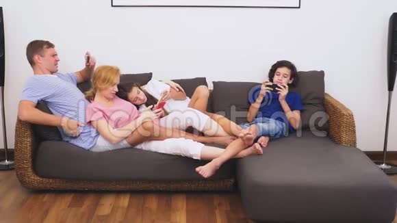 可爱的家人妈妈爸爸女儿和儿子一起在客厅看电视每个人都在看他的电视视频的预览图