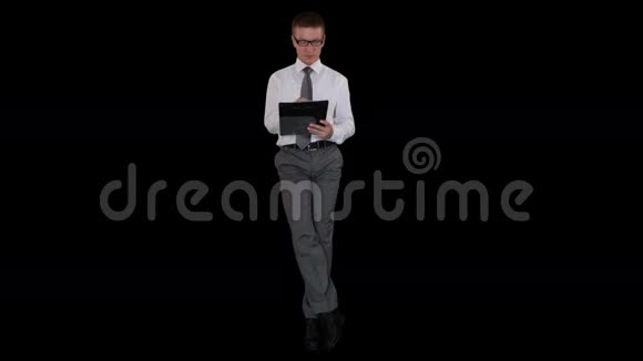 年轻的商人戴着眼镜在剪贴板上扭动坐着面对黑色的股票录像视频的预览图