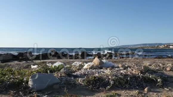 沙滩上的塑料袋和纸垃圾海浪在背景上撞击海滩慢动作视频的预览图