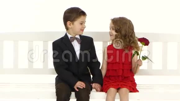 孩子们骑着秋千一个小男孩亲吻女孩的脸颊白色背景视频的预览图