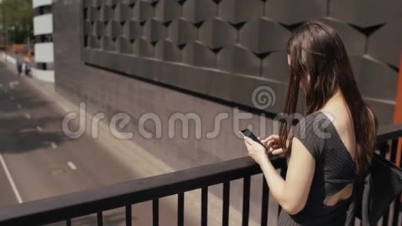 商务女性使用智能手机站在桥上俯瞰道路Stealicam拍摄慢节奏视频的预览图