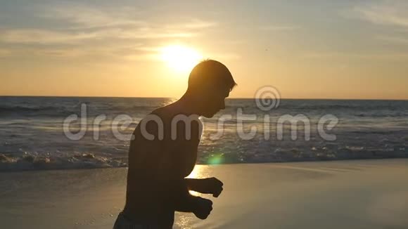 日出时运动员沿着海岸慢跑日落时分一个运动的年轻人在海边奔跑男性视频的预览图