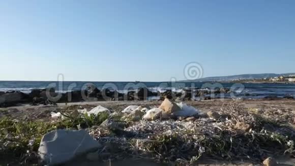 沙滩上的塑料袋和纸垃圾海浪在背景上撞击海滩视频的预览图