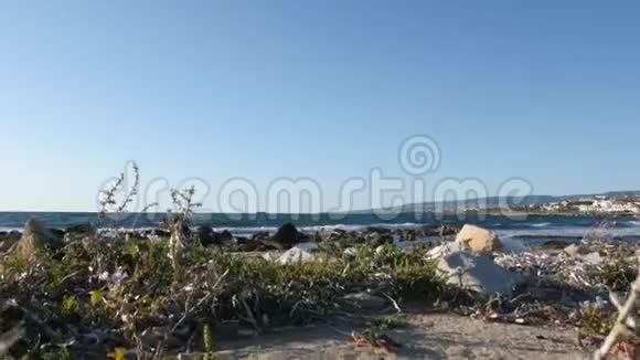 白色塑料袋在岩石海滩上波浪撞击悬崖的背景海滩污染概念慢动作视频的预览图