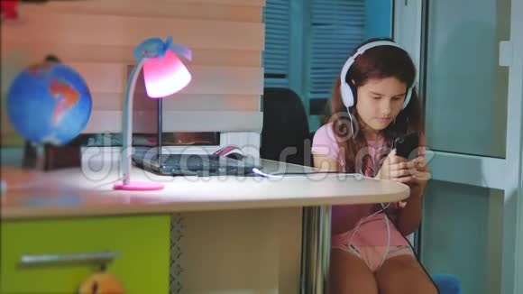 小女孩在智能手机上耳机听音乐青少年女孩在生活方式中翻阅播放列表音乐视频的预览图
