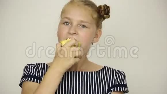 美丽的年轻女孩穿着条纹连衣裙吃苹果健康食品坚固的牙齿概念视频的预览图