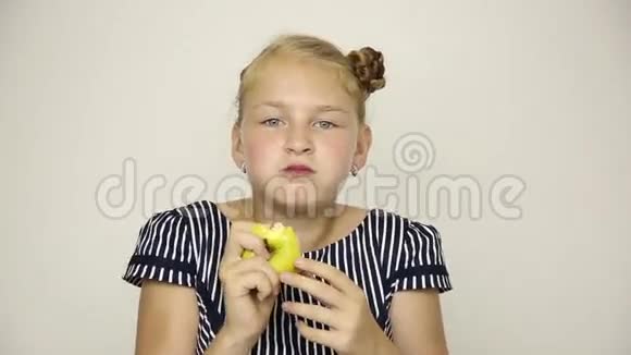 美丽的年轻女孩穿着条纹连衣裙吃苹果健康食品坚固的牙齿概念视频的预览图