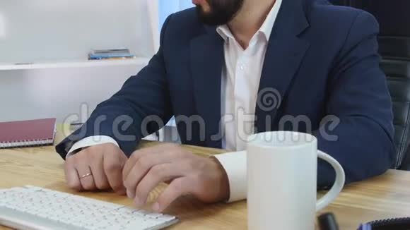 一个高兴的商人坐在他的办公室里在他的电脑前工作视频的预览图