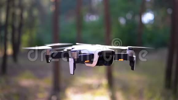 带着相机的无人机在森林里的地面上空盘旋动作缓慢视频的预览图