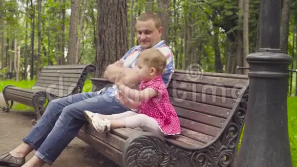 爸爸和小女孩坐在长凳上视频的预览图