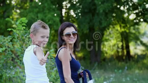 一个女人和一个男孩在田野里走来走去儿子骑着一匹小马母亲拿着一匹小马做缰绳快乐视频的预览图