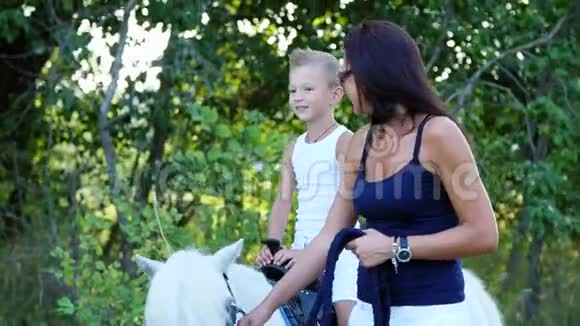 一个女人和一个男孩在田野里走来走去儿子骑着一匹小马母亲拿着一匹小马做缰绳快乐视频的预览图