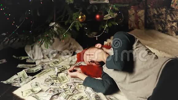 一个男人带着钱睡在圣诞树下视频的预览图