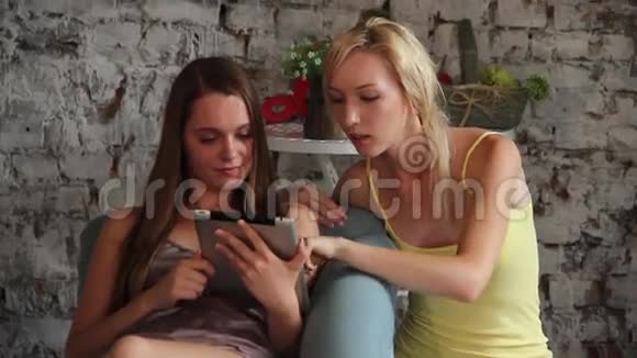 两个年轻女人看着平板电脑聊天视频的预览图