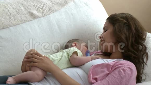 可爱的年轻母亲和她的孩子躺在沙发上视频的预览图