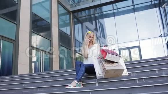 一个女孩在购物后带着漂亮的包裹打电话给她的朋友讲述折扣和销售视频的预览图