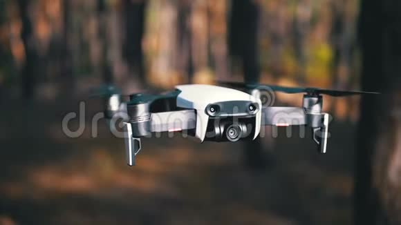 带着摄像机的无人机在森林里的地面上空盘旋慢动作视频的预览图