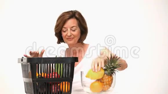 高级妇女把水果放进碗里视频的预览图