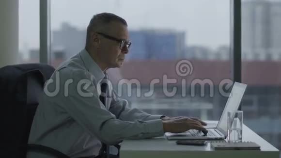 老商人在现代办公室里用电脑工作他的背疼视频的预览图