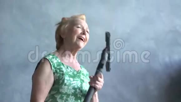 快乐的老年妇女与吸尘器跳舞家庭乐趣视频的预览图