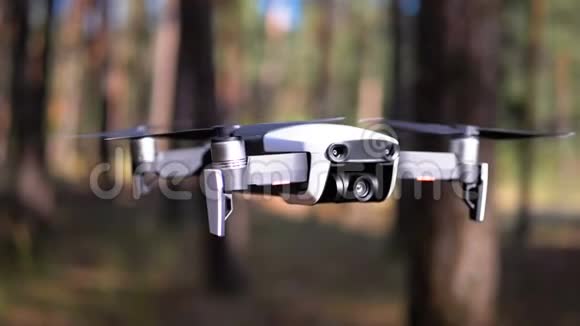 带着相机的无人机在森林里的地面上空盘旋动作缓慢视频的预览图