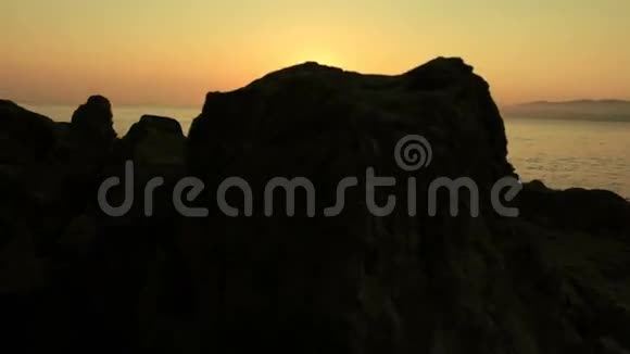 在海滩上对着日出在石头前面视频的预览图