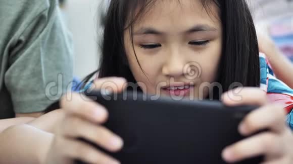 亚洲男孩和女孩一起玩手机游戏带着笑脸视频的预览图