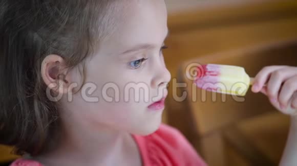 美丽的小女孩吃着美味的彩色冰淇淋视频的预览图