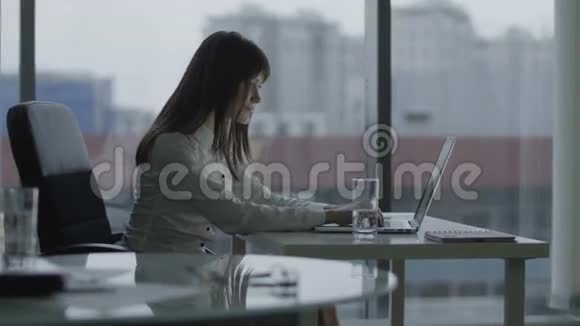 年轻的商业女性在现代办公室的笔记本电脑上工作她微笑着休息一下视频的预览图
