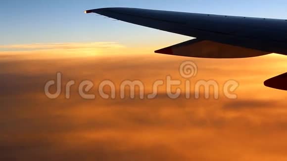 橙色云层上方的飞机机翼视频的预览图