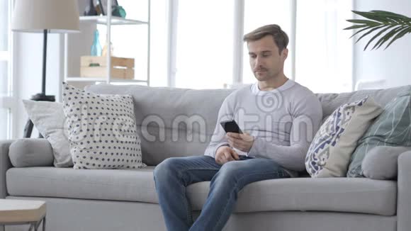 坐在沙发上打电话的成年男子视频的预览图
