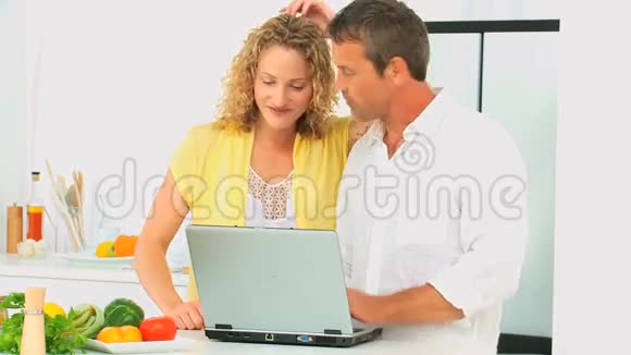 可爱的一对夫妇看着笔记本电脑上的食谱视频的预览图