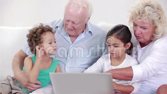 两个祖父母和两个孩子用笔记本电脑视频的预览图
