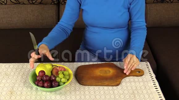 年轻孕妇亲手切梨做水果沙拉特写镜头视频的预览图