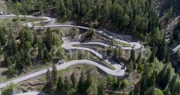 乘坐卡车和汽车在锯齿形上行驶的高山蛇形公路的鸟瞰图在欧洲瑞士上下行视频的预览图