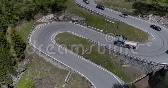 乘坐卡车和汽车在锯齿形上行驶的高山蛇形公路的鸟瞰图在欧洲瑞士上下行视频的预览图