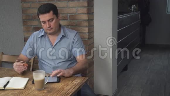 中年人通过互联网支付信用卡手中的账单桌子上有一杯咖啡视频的预览图