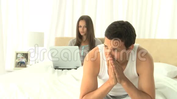 一个伤心的男人在想他妻子在用笔记本电脑视频的预览图